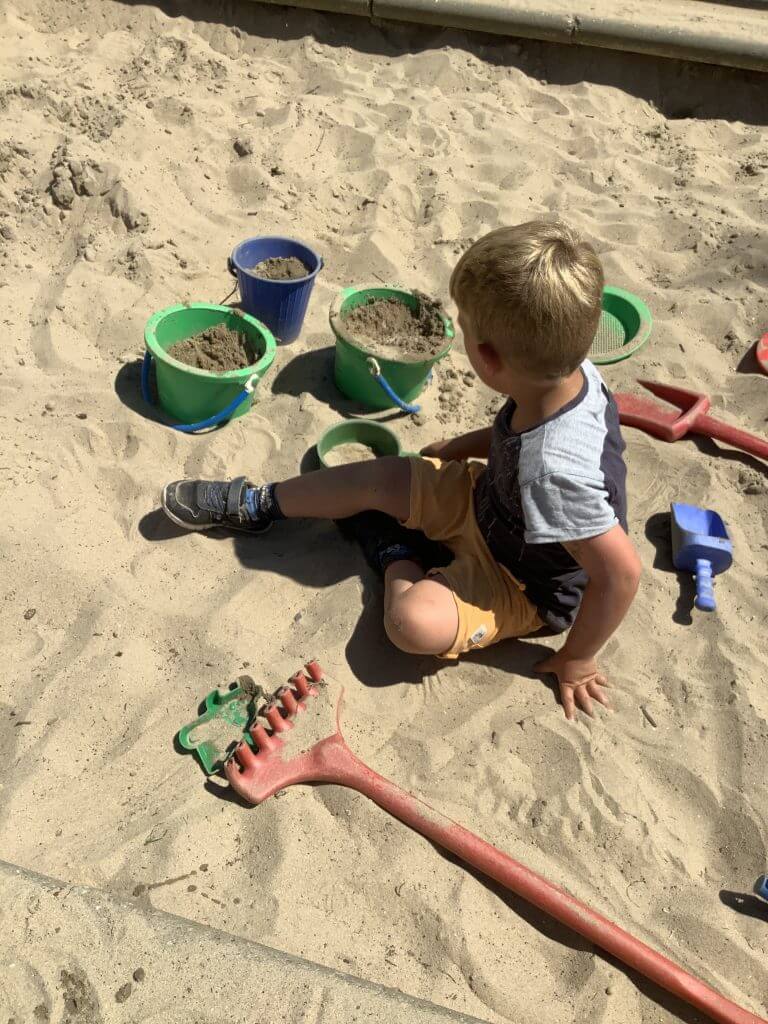 jongen speelt in de zandbak