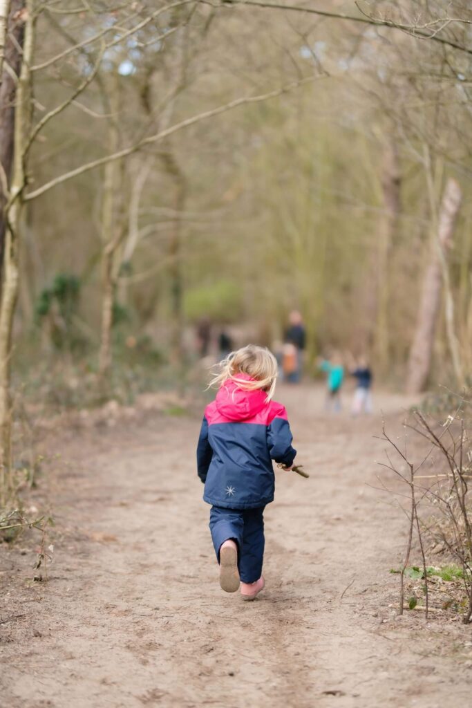 Kind loopt in het bos met de outdoor bso
