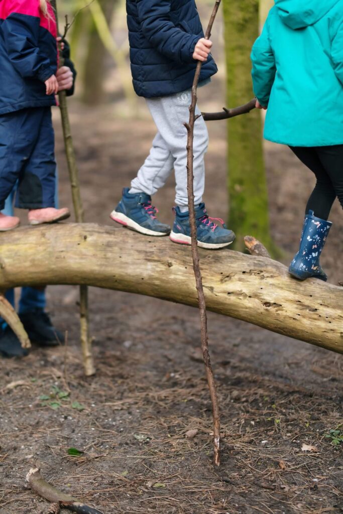 Kinderen lopen over een boomstam bij de Outdoor BSO