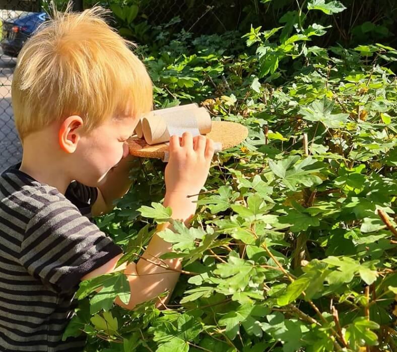 Zo Kinderopvang locatie Van Nijenrodestraat jongen kijkt door houten verrekijker in het bos