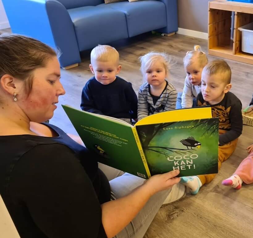 Zo Kinderopvang locatie Zo Aan de Postweg pedagogische medewerker leest voor uit boek aan groepje kinderen
