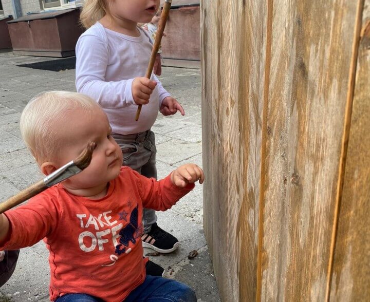 Kinderen verven de houten schutting bij Zo aan de Van der Wyckstraat