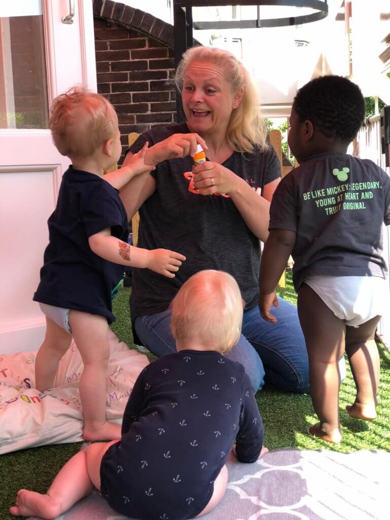 Pedagogisch medewerker speelt met bellenblaas met de kinderen