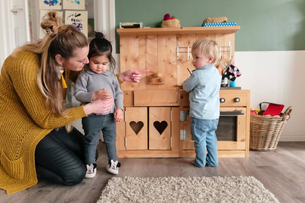 Kinderen en pedagogisch medewerker spelen bij de speelkeuken op de kinderopvang