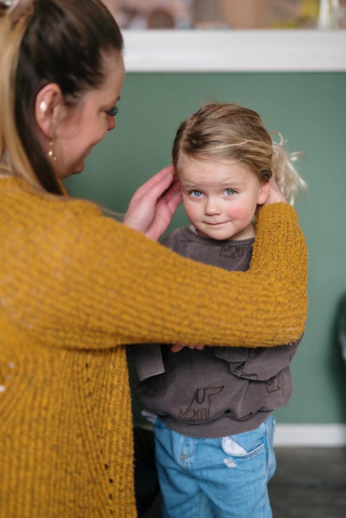 pedagogische medewerker doet de haren van een meisje