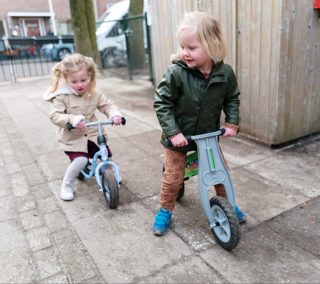 Kinderen spelen buiten op fietsjes bij Zo kinderopvang