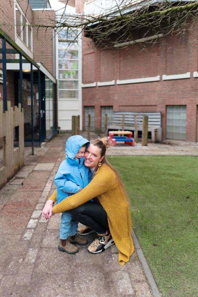 pedagogische medewerker omhelst meisje met capuchon