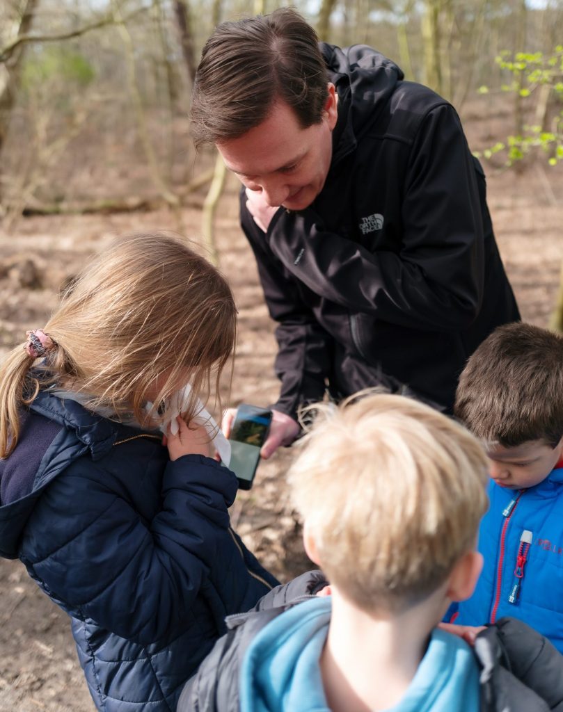 Zo Kinderopvang pedagogische medewerker laat foto zien op zijn mobiele telefoon aan de kinderen
