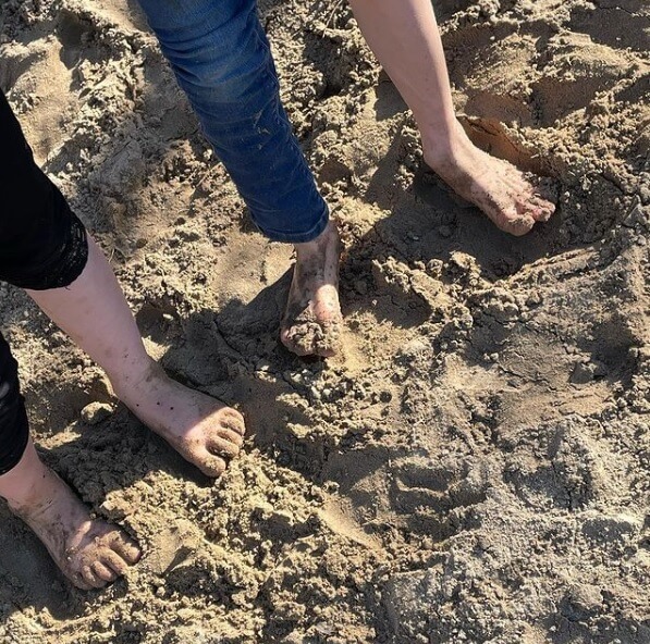 Kinderen staan met de blote voeten in het zand