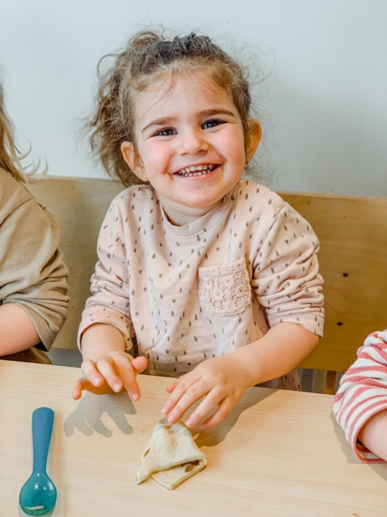 klein meisje lacht en is deeg aan het kneden