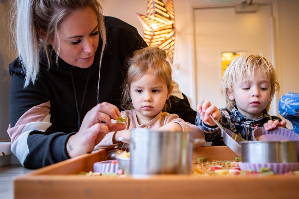 pedagogisch medewerker laat pasta vormpje zien aan klein meisje