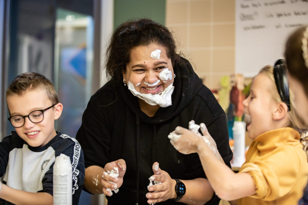 pedagogisch medewerker speelt samen met kinderen met scheerschuim