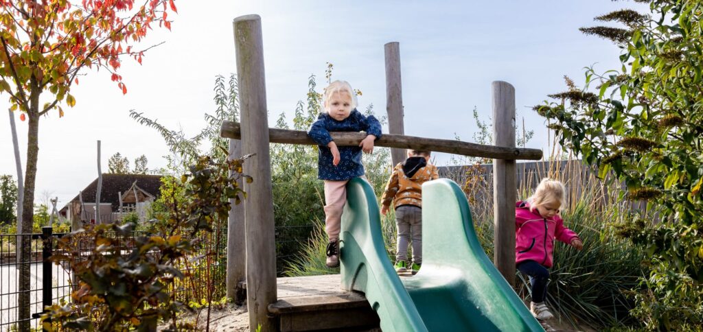 Kinderen spelen buiten bij de glijbaan op de dagopvang