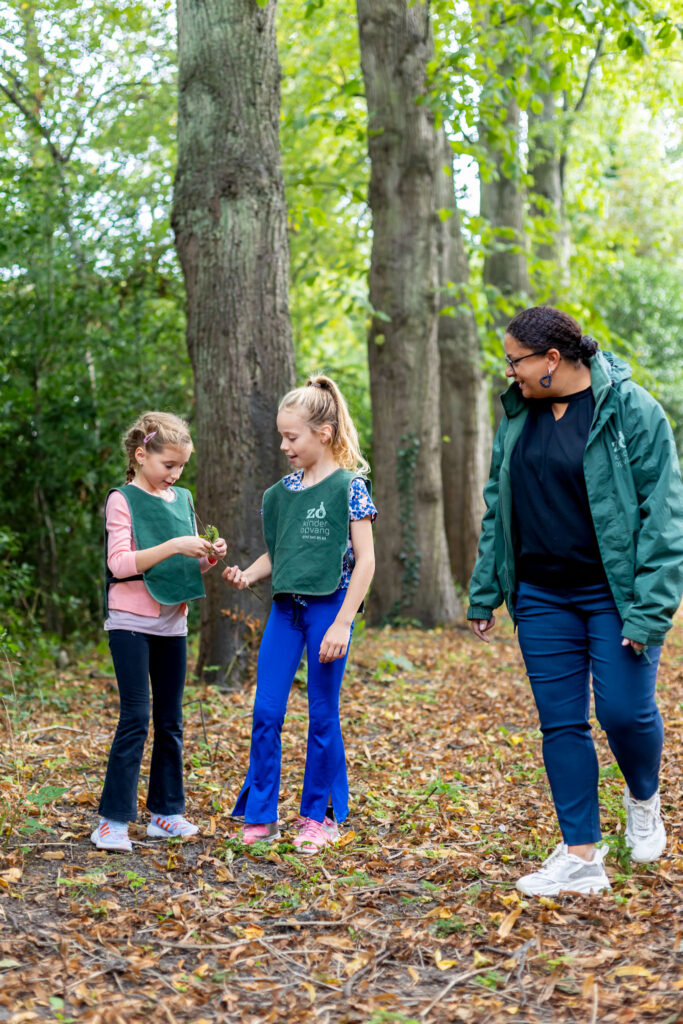 Zo Kinderopvang pedagogisch medewerker observeert twee spelende kinderen in de natuur