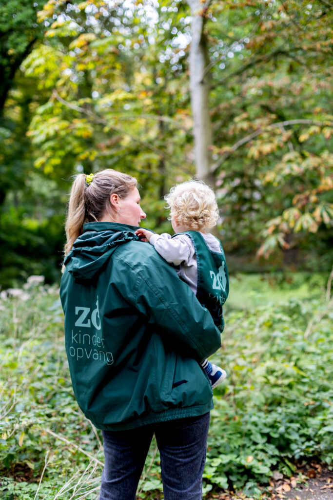 Zo Kinderopvang pedagogisch medewerker houdt kind in de armen in het bos