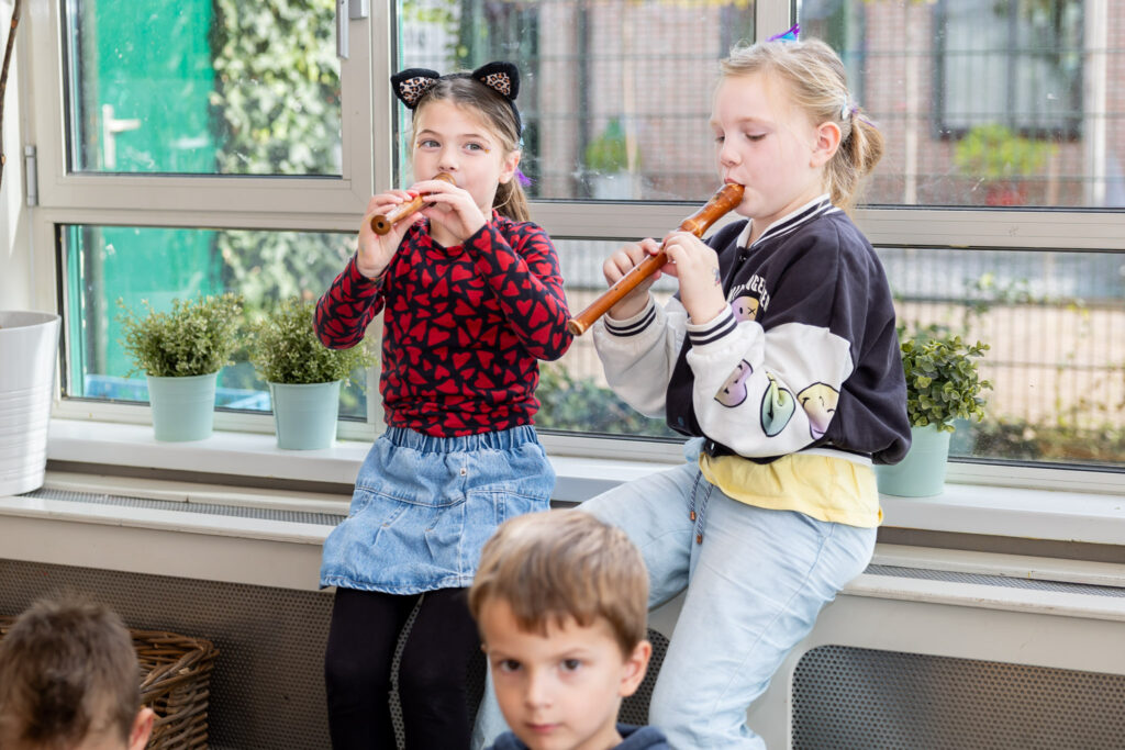 Twee meisjes spelen blokfluit tijdens de muziekles op de kinderopvang