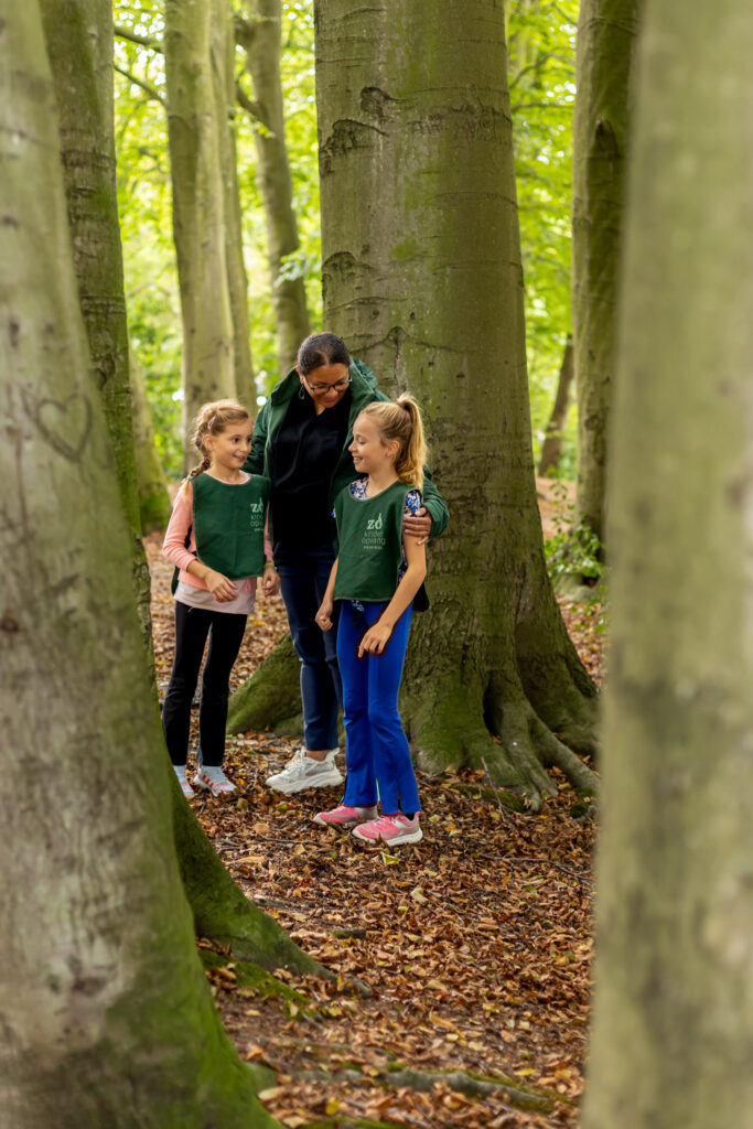 Pedagogisch medewerker staat met bso kinderen in het bos
