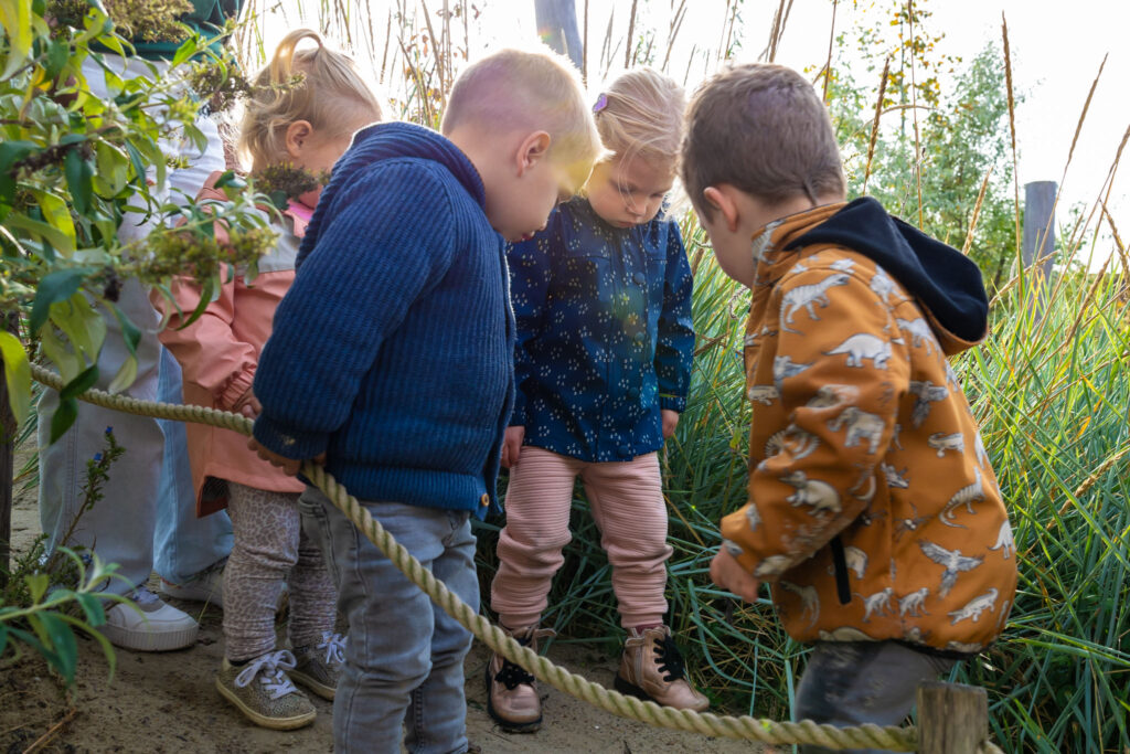 Peuters staan buiten in de buitenspeeltuin bij de peuteropvang