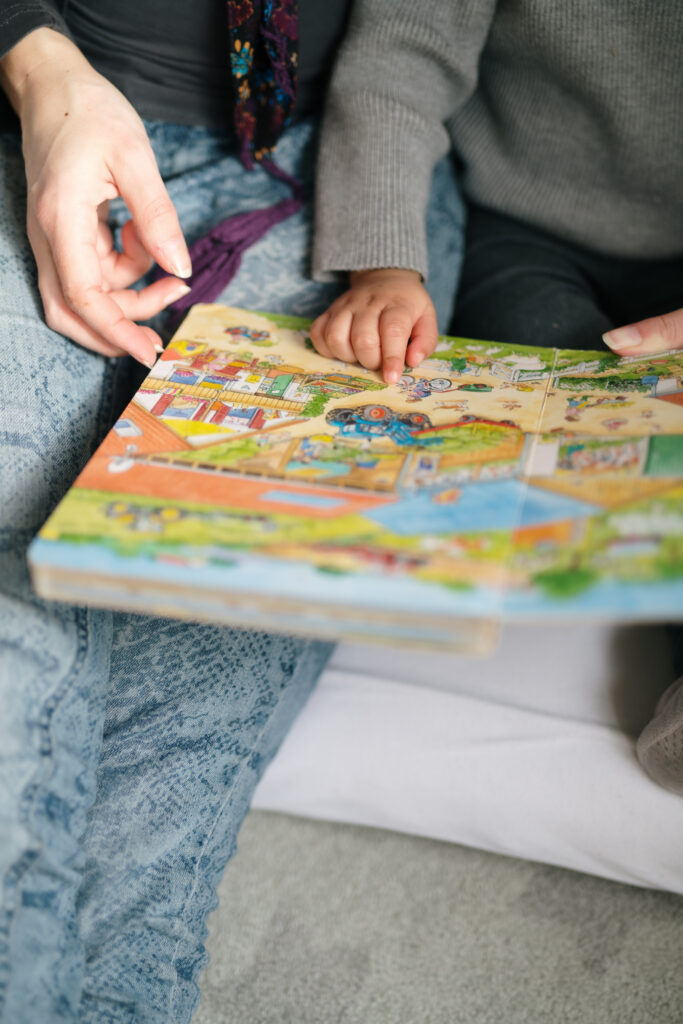 Kind leest in een prentenboekje en wijst iets aan